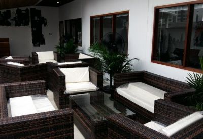 Outdoor lounge area featuring brown wicker furniture with white cushions.