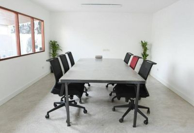 Bright, minimalist meeting room with a large table and black mesh chairs.
