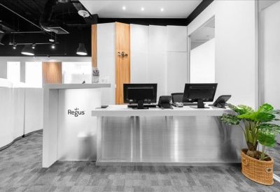 Professional reception desk area with wood accents, dual monitors, and a vibrant potted green plant.