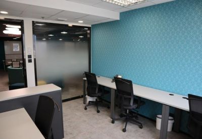 Modern workspace with long desks against a teal patterned feature wall.