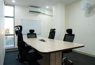 Professional meeting room featuring a light wood table, black chairs, and a whiteboard.