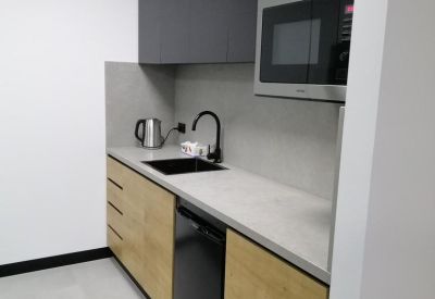 Modern office kitchenette with timber cabinetry, grey overhead cupboards, and integrated microwave.