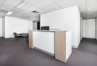 Modern white reception desk with light wood accents in a bright, open lobby area.