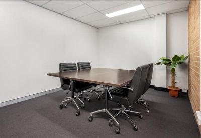 Professional meeting room with a dark wood table, black leather chairs, and a potted plant.
