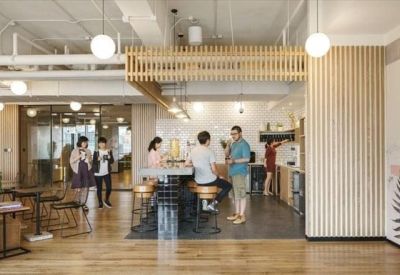 Modern kitchen and coworking space with wooden slat walls, pendant lighting, and people socializing.