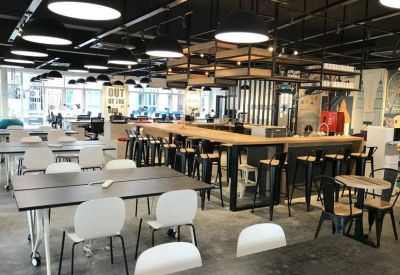 Spacious coworking space with multiple desk arrangements and bar seating.