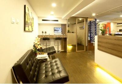 Modern lobby area featuring a black leather bench, wooden accents, and a small computer workstation.