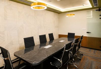 Professional boardroom with a large marble-patterned table and yellow ring pendant lights.