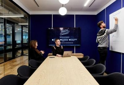 Dark blue meeting room with a large white board and a long timber table.