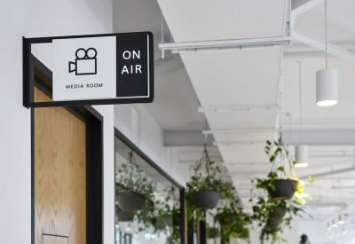 Modern signage for an On Air media room in a bright hallway with hanging plants.