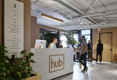 Reception area featuring a white front desk with Hub branding and warm wood paneling.