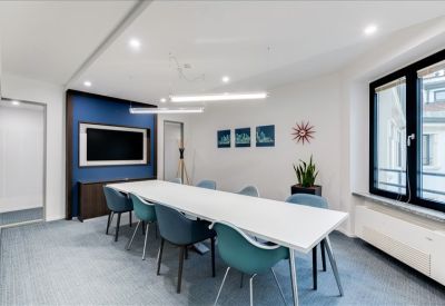 Modern conference room with teal chairs, a blue feature wall, and a large wall-mounted screen.