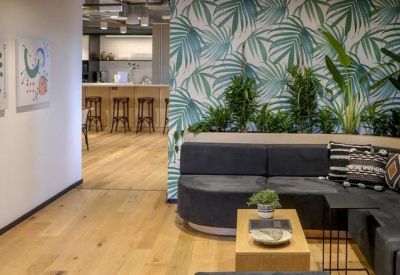 Relaxation area with a dark grey sectional sofa against a vibrant tropical leaf wallpaper.