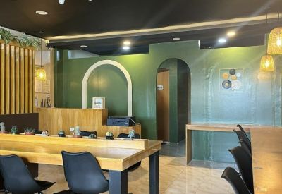 Modern coworking space with wood-top communal desks, black rolling chairs, and a green feature wall.