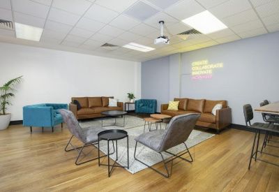 Casual breakout lounge with brown leather sofas, teal armchairs, and a projector screen.