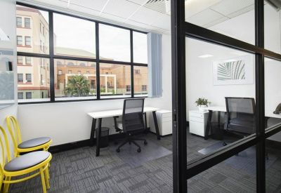 Bright corner office with two desks and large windows overlooking the street.