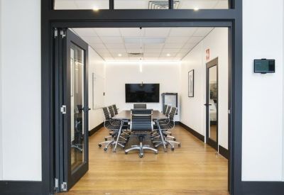 Spacious boardroom with a large black conference table and glass folding doors.