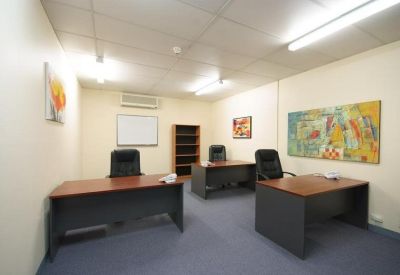 Private office suite with three wooden desks and colourful wall art.