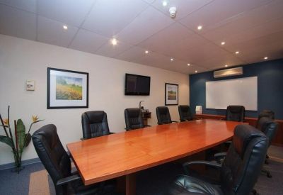 Boardroom featuring a large wooden table, black leather chairs, and a white presentation board.