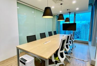 Long wooden boardroom table with modern white chairs and black pendant lighting.