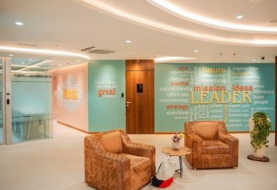 Bright reception area with teal feature walls, branded leader graphic, and brown leather armchairs.