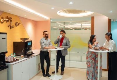 Communal break area with a coffee station, high-top tables, and warm peach-toned walls.