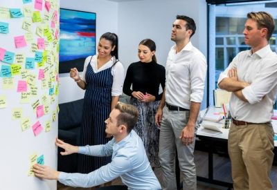 Group of colleagues collaborating around a white wall covered in colorful sticky notes.