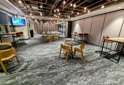 Open breakout space with varied seating arrangements, patterned carpet, and feature pipe lighting.