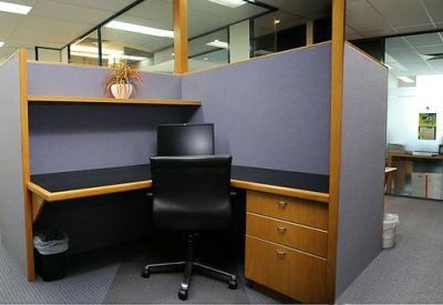 Corner workstation with a purple privacy screen and wooden drawers.