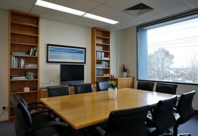 Spacious boardroom with a large wooden table and natural light from a window.
