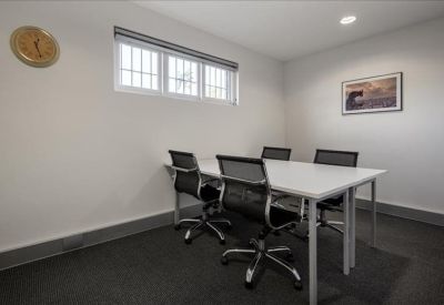 Minimalist four-person meeting room with a small window and wall art.
