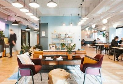 Modern coworking lounge with colorful armchairs and a decorative light installation.
