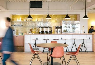 Cafe-style breakout area featuring a white tiled bar, high stools, and warm pendant lighting.