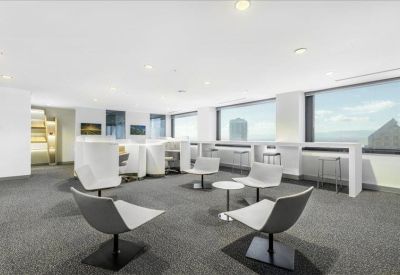 Bright communal lounge and breakout area with modern white armchairs and window-side bar seating.