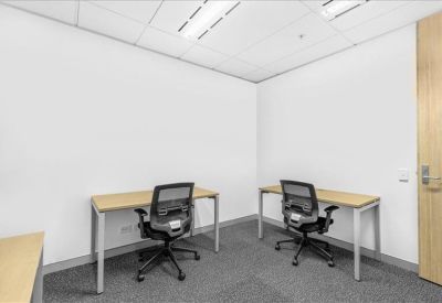Internal two-person office suite with simple wooden desks and mesh chairs.