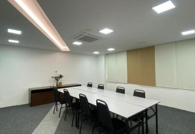 Brightly lit meeting room with a long white table and black chairs.
