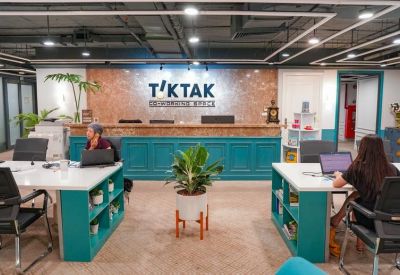 Modern reception desk with teal paneling and a branded backdrop behind white workstations.