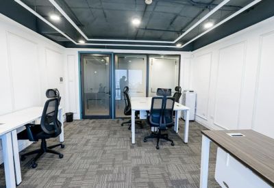 Private office suite with white desks, ergonomic mesh chairs, and large glass windows.