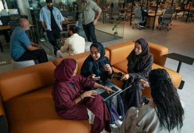 Professionals having an informal meeting on orange sofas in a lounge area.