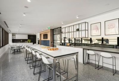 Communal breakout area with long high-top tables and a sleek modern kitchen.