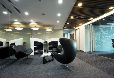 Modern lounge area with stylish black egg chairs and a unique coffee table on a grey carpet.
