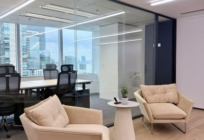 Bright breakout area with plush cream armchairs and city views through glass partitions.