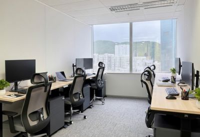 Four-person private office with wooden desks, ergonomic chairs, and large window overlooking the city.