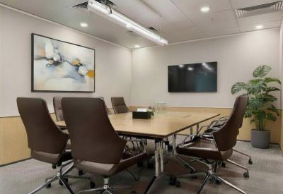 Professional meeting room with a large light wood table, brown leather chairs, and abstract wall art.