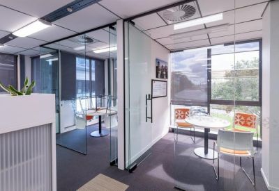 Bright private meeting room with glass walls and a small round table.
