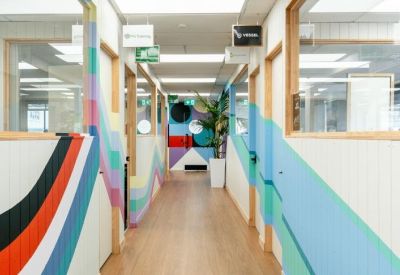 Bright hallway featuring vibrant geometric wall murals and light wood flooring.