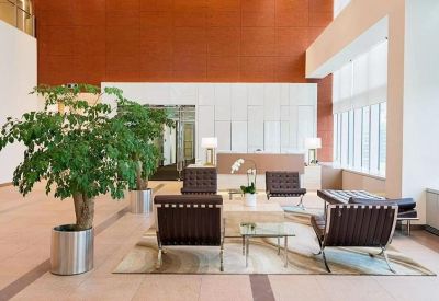 Spacious corporate lobby with high ceilings, indoor trees, and leather seating areas.