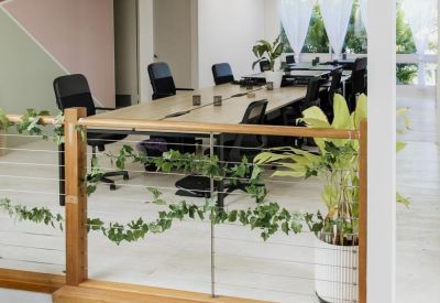 Long wooden shared workstation with cable management and green vines on the railing.