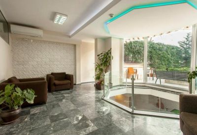 Bright hallway lounge area with marble floors and views of lush greenery through large windows.