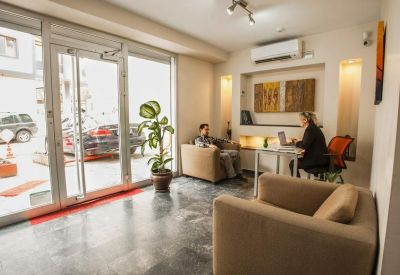 Modern lobby area with comfortable armchairs and a glass door entrance reflecting a car outside.
